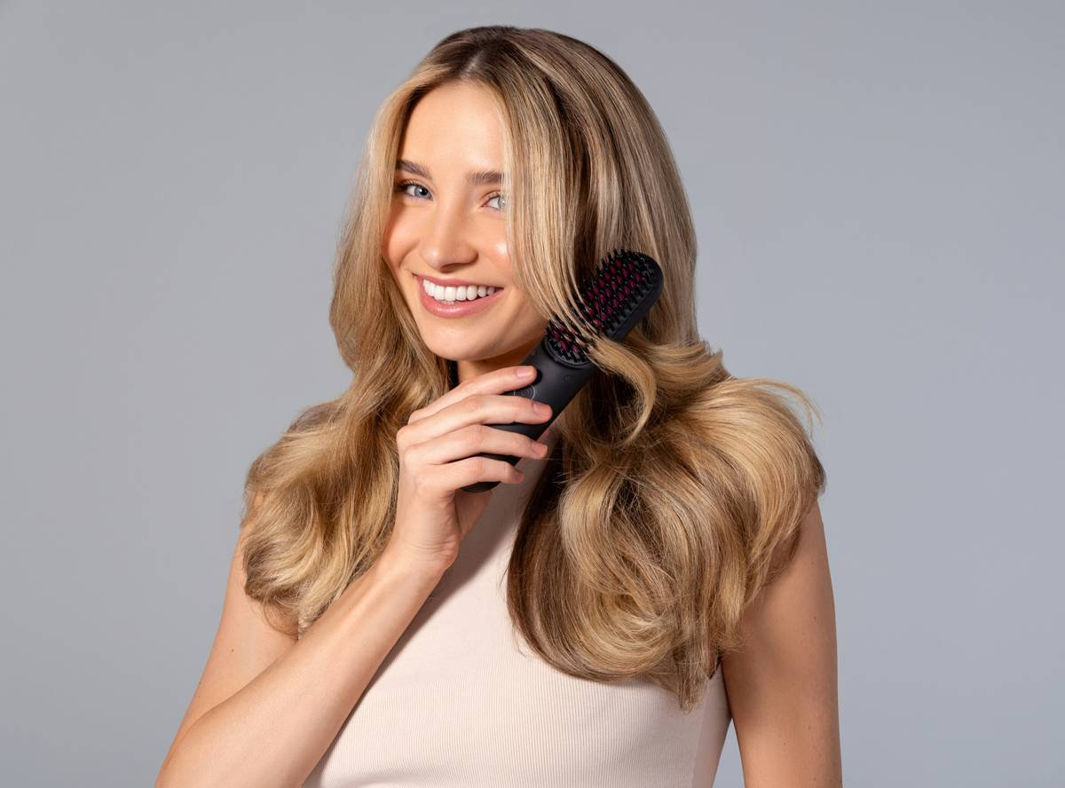 Woman using a hair detangling brush on damp curly hair with proper sectioning technique