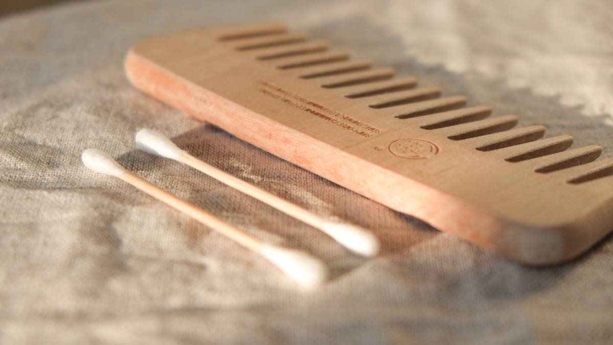 Close-up of hand using wooden hair picks to lift natural curls gently