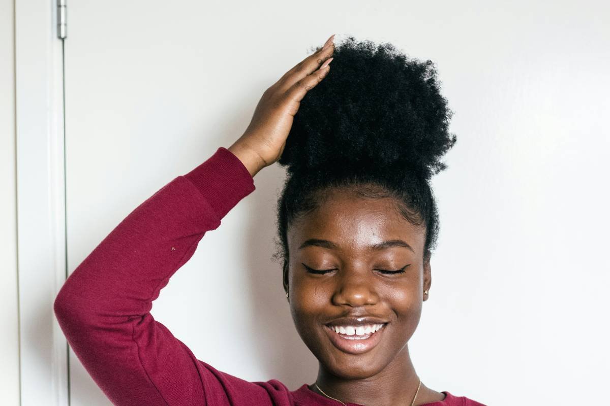 Woman gently detangling kinky hair with a wide-tooth hair pick for kinky hair care